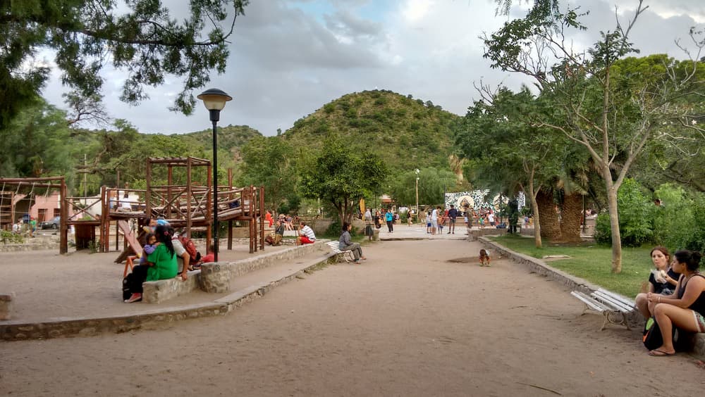 Parque con juegos, personas y vegetación alrededor