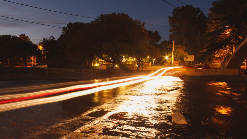 Fotografía de larga exposición en calle asfaltada con auto pasando